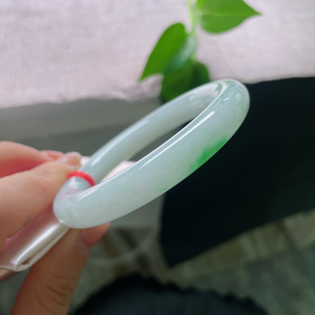 53.1/10，飘绿圆条，一点皮纹，一抹鲜翠悄然落于镯身，翠色灵动鲜活，如春风拂过山间碧潭，清逸温婉。ss56713a
