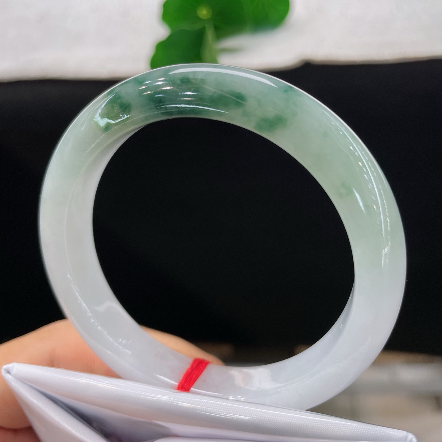 圈口56.9/10.9/8，飘花正圈，脂润莹白基底晕开缥缈墨绿飘花，质地细腻。