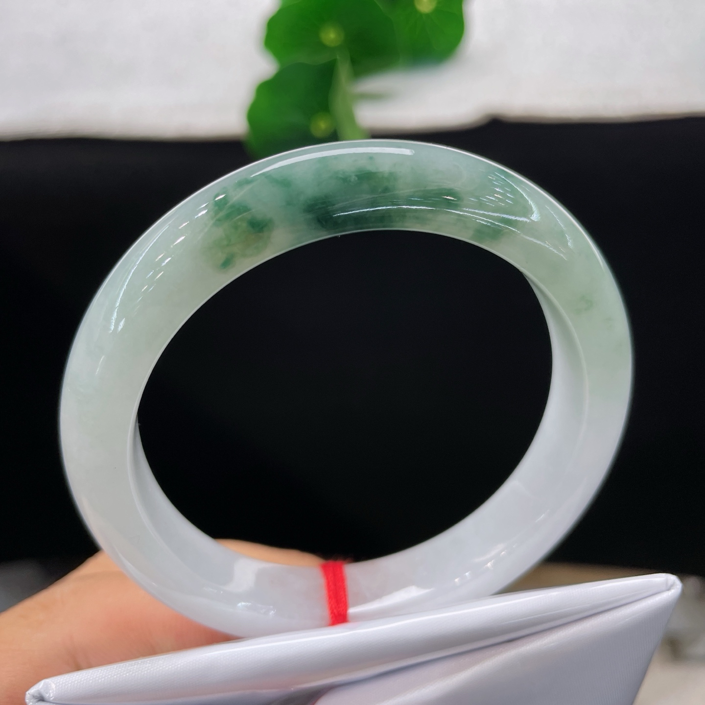 圈口56.9/10.9/8，飘花正圈，脂润莹白基底晕开缥缈墨绿飘花，质地细腻。