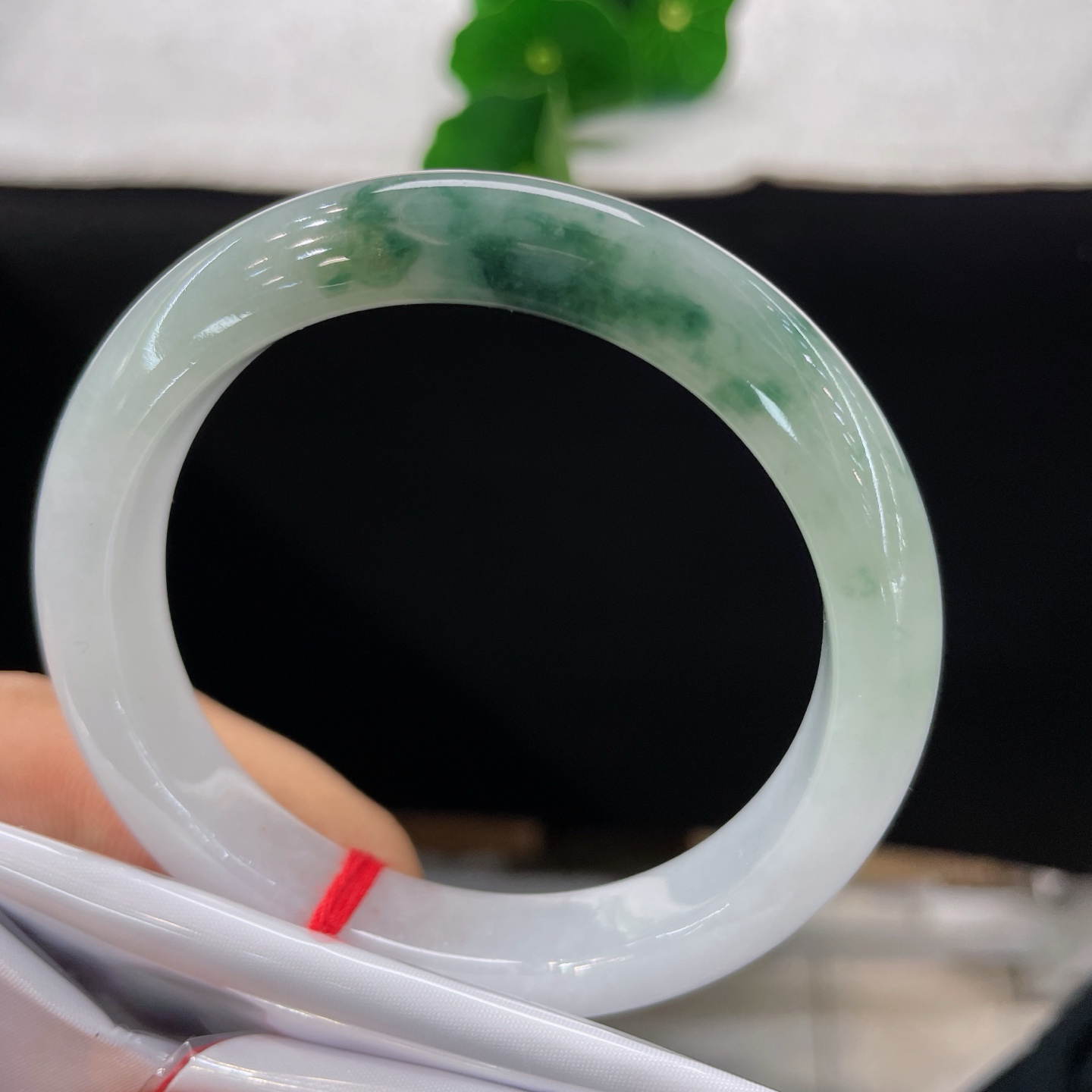 圈口56.9/10.9/8，飘花正圈，脂润莹白基底晕开缥缈墨绿飘花，质地细腻。
