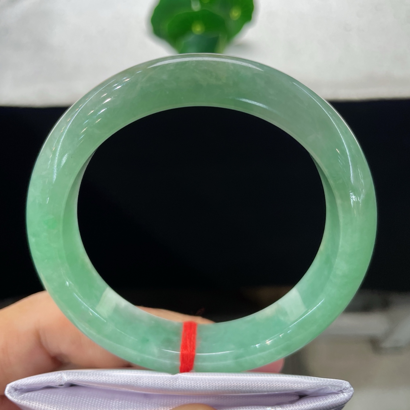 圈口57.3/13.5/9，果绿正圈，57/58可戴，仿若翠潭漾波，质地温润澄澈。色泽均匀清雅。无裂。