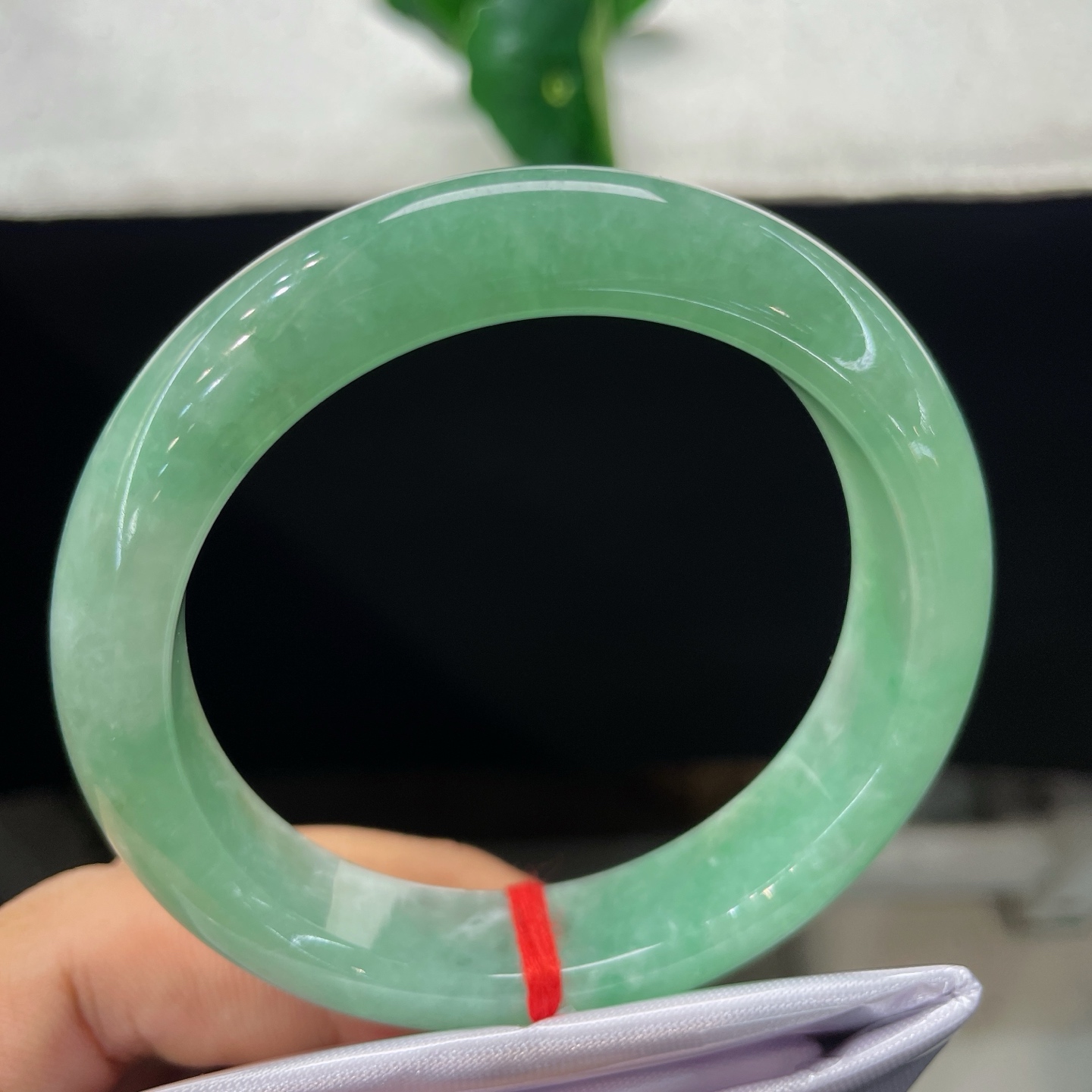 圈口57.3/13.5/9，果绿正圈，57/58可戴，仿若翠潭漾波，质地温润澄澈。色泽均匀清雅。无裂。