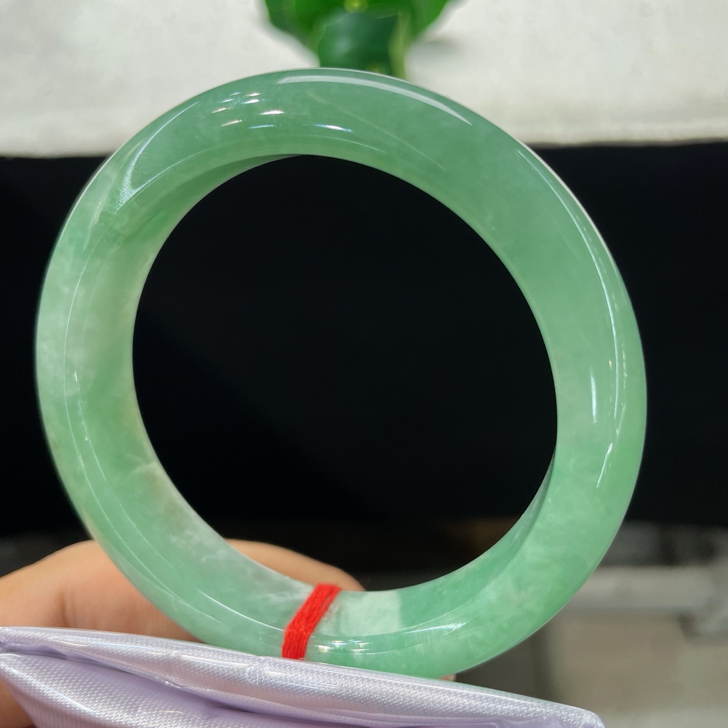 圈口57.3/13.5/9，果绿正圈，57/58可戴，仿若翠潭漾波，质地温润澄澈。色泽均匀清雅。无裂。