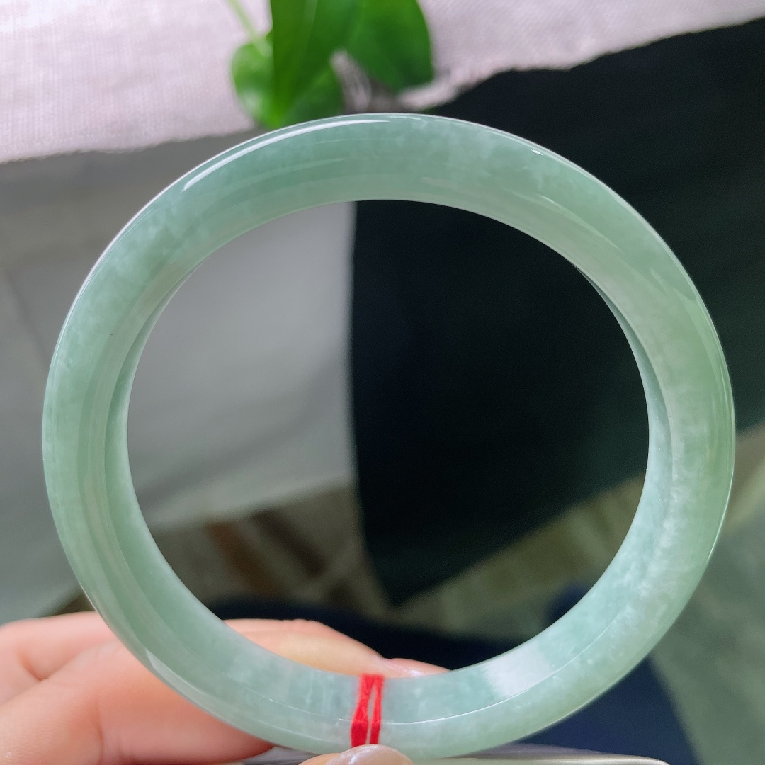 绿底正圈，无裂，镯面光泽温润内敛，不浮不燥，光线漫过镯身，尽显玉石浑厚的底蕴。ss57932a