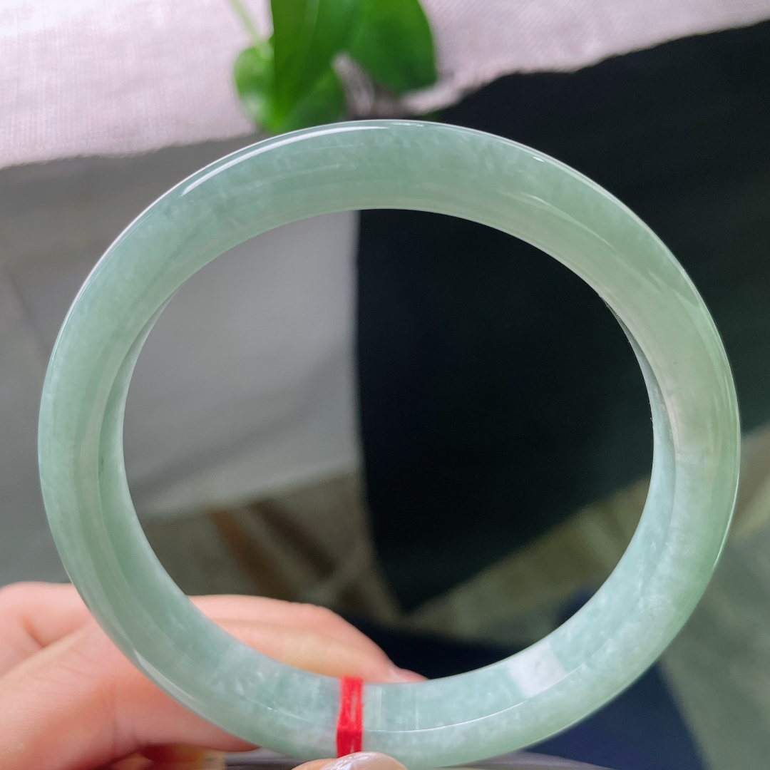 绿底正圈，无裂，镯面光泽温润内敛，不浮不燥，光线漫过镯身，尽显玉石浑厚的底蕴。ss57932a