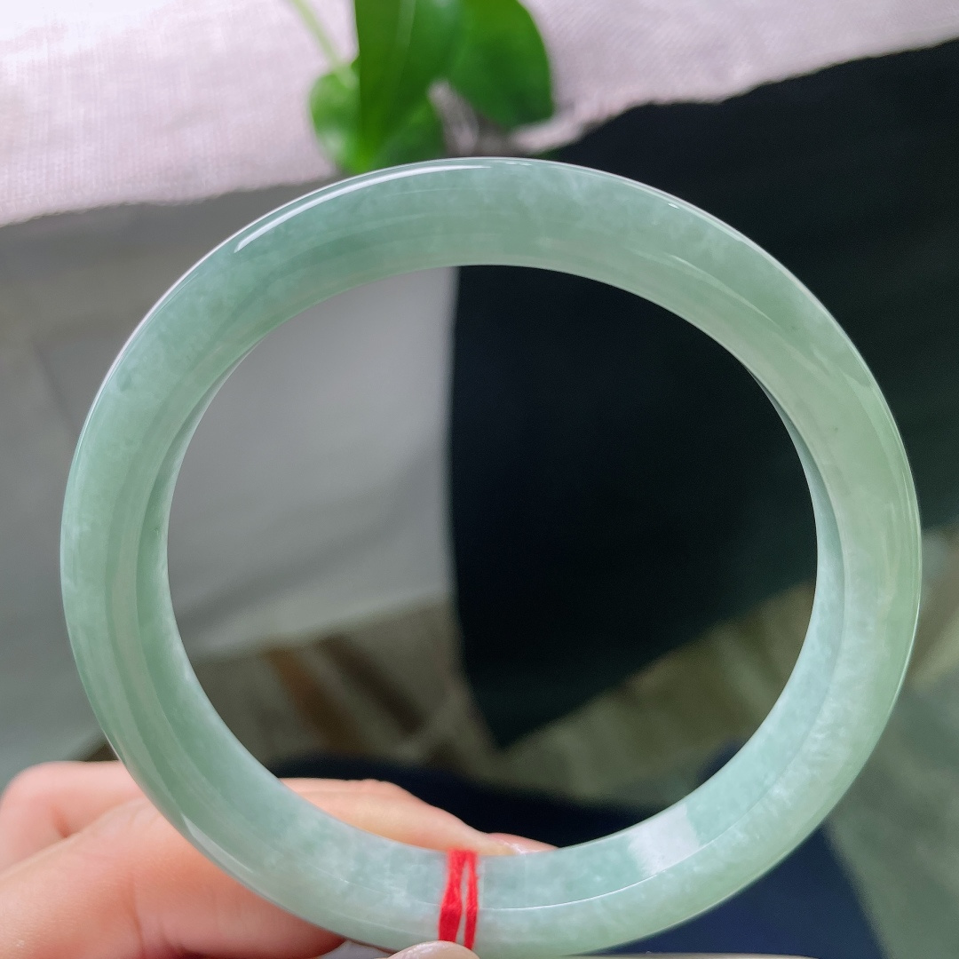 绿底正圈，无裂，镯面光泽温润内敛，不浮不燥，光线漫过镯身，尽显玉石浑厚的底蕴。ss57932a