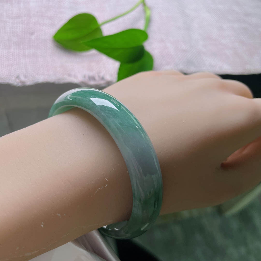 油青贵妃，一点皮纹，冰润飘绿正圈平安镯，半圈是清透的冰种底质，翠色如烟如云，自然飘散于镯身。ss58020a