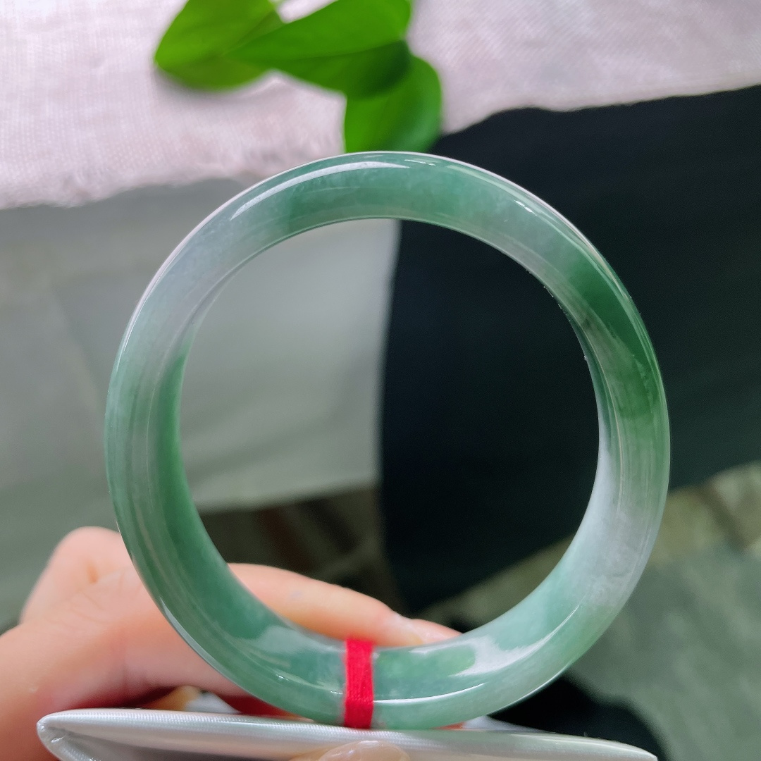 油青贵妃，一点皮纹，冰润飘绿正圈平安镯，半圈是清透的冰种底质，翠色如烟如云，自然飘散于镯身。ss58020a