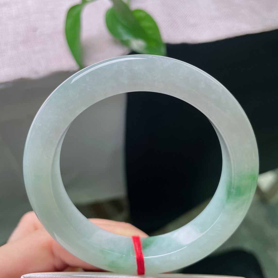 55/12.9/9.8，飘花正圈，有棉线，玉质温润细腻，柔光静静流淌，不似浓艳珠宝那般张扬，点点飘绿恰到好处，悄悄点亮整只镯子的灵气。ss58045a