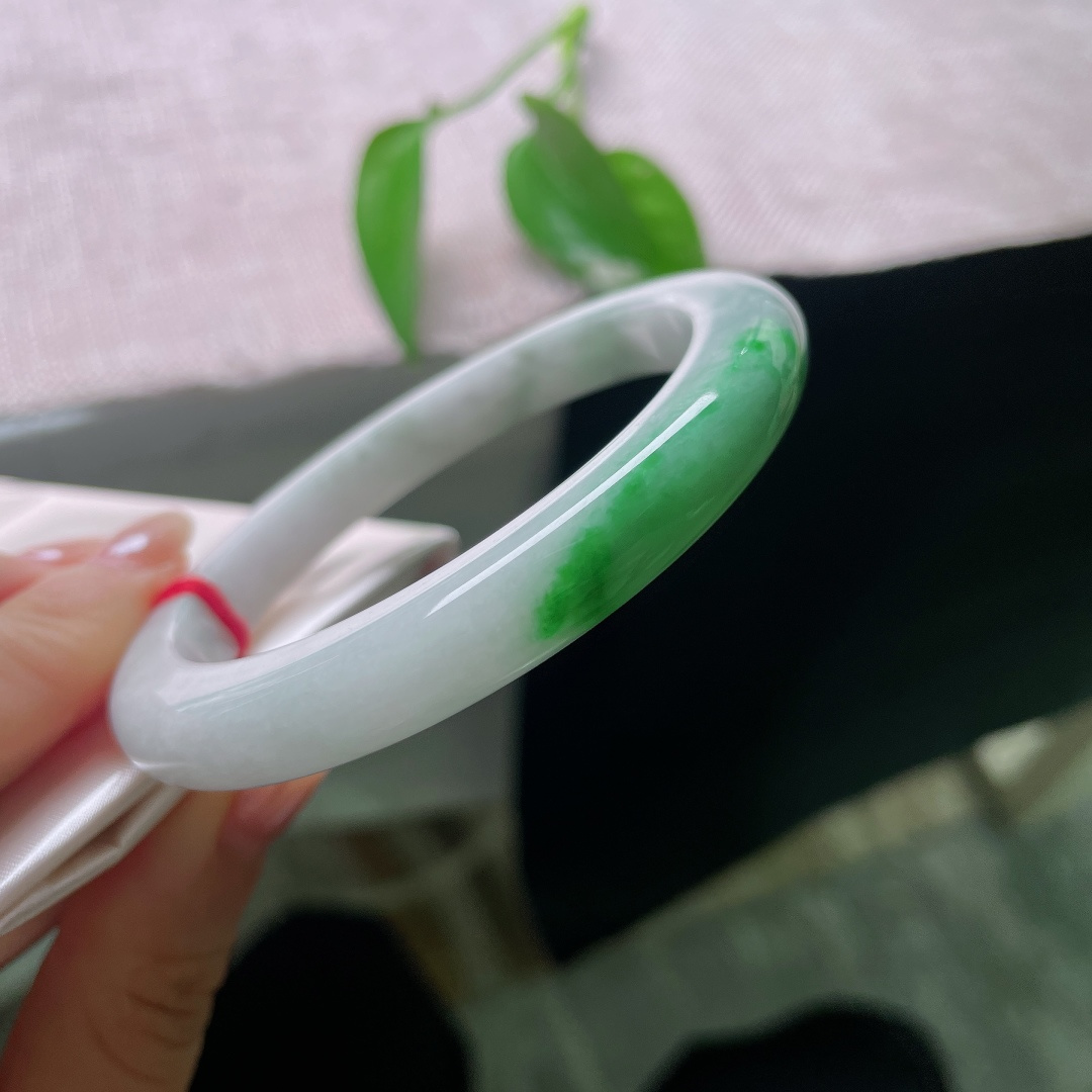 飘绿正圈，一点皮纹，镯身整体清润柔和，局部翠色若隐若现，留白干净，青绿点睛。ss57989a