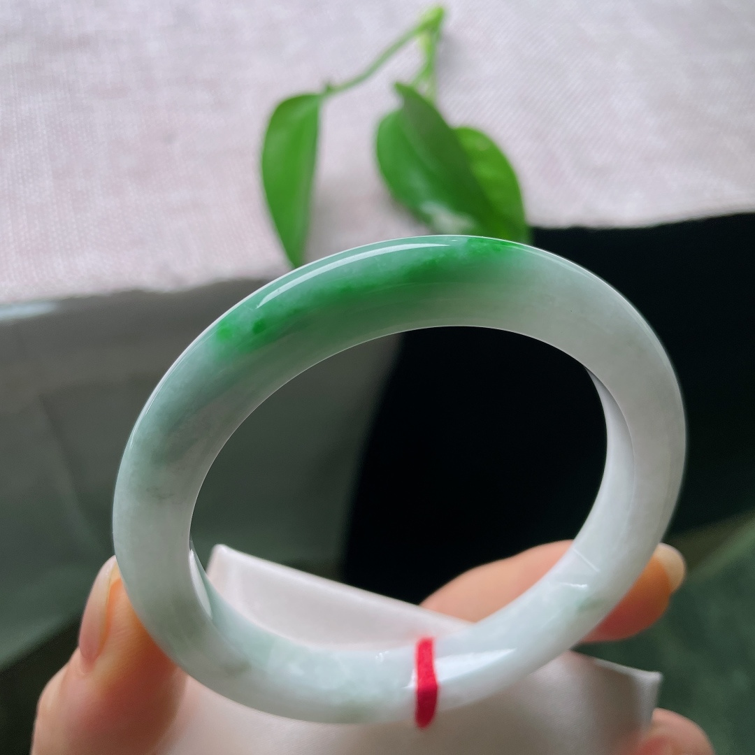 飘绿正圈，一点皮纹，镯身整体清润柔和，局部翠色若隐若现，留白干净，青绿点睛。ss57989a