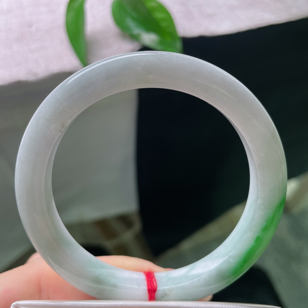 飘绿正圈，一点皮纹，镯身整体清润柔和，局部翠色若隐若现，留白干净，青绿点睛。ss57989a