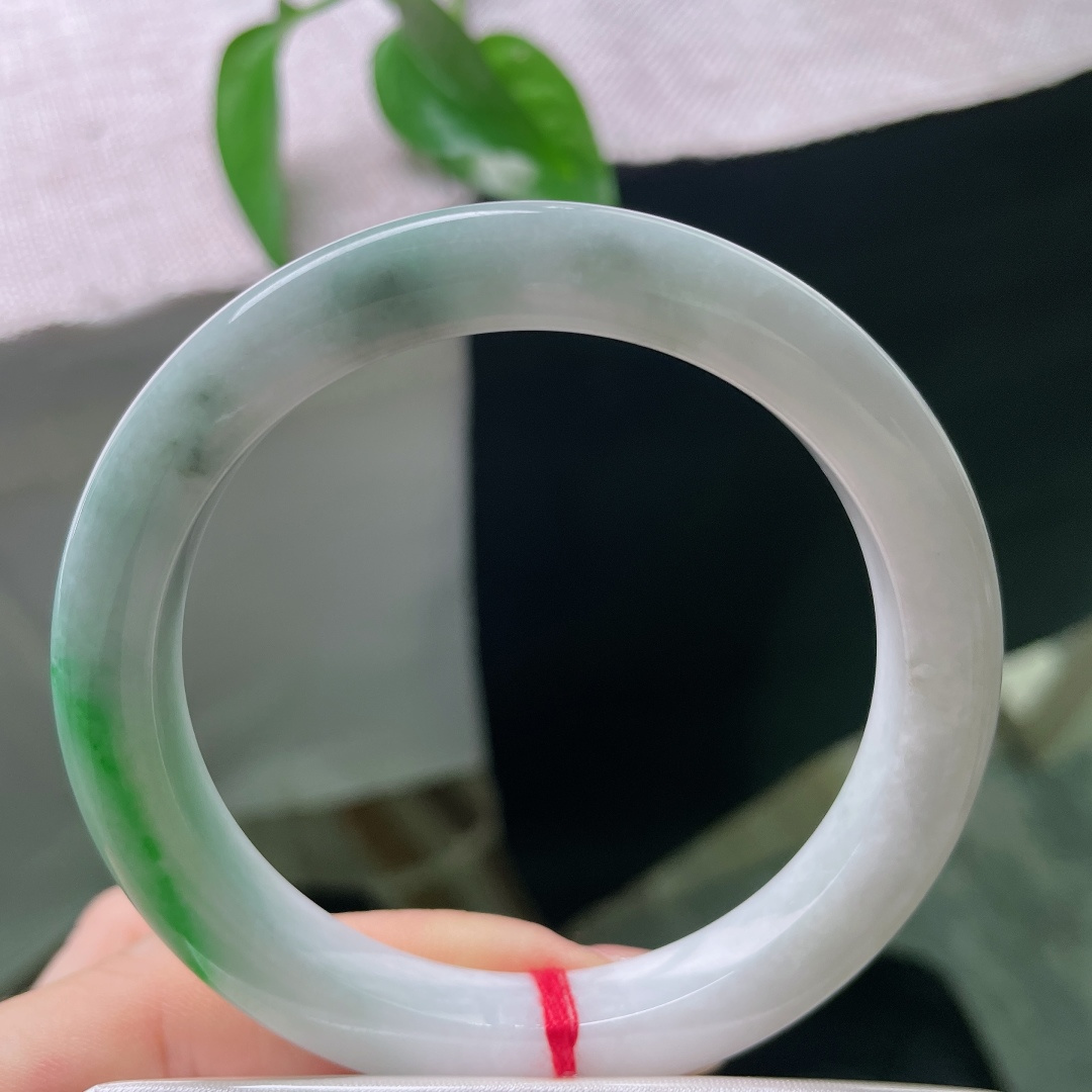 飘绿正圈，一点皮纹，镯身整体清润柔和，局部翠色若隐若现，留白干净，青绿点睛。ss57989a