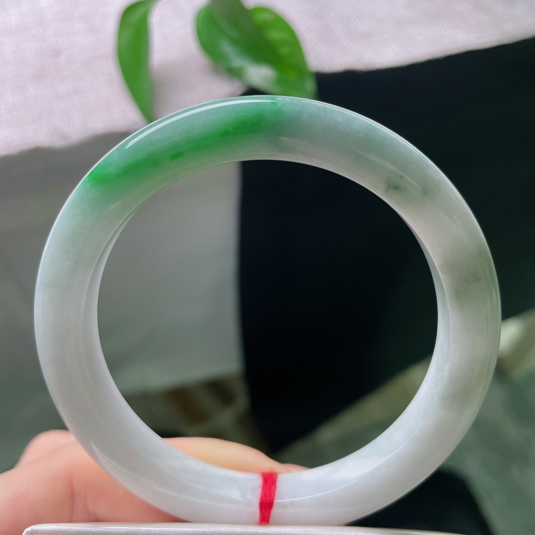 飘绿正圈，一点皮纹，镯身整体清润柔和，局部翠色若隐若现，留白干净，青绿点睛。ss57989a