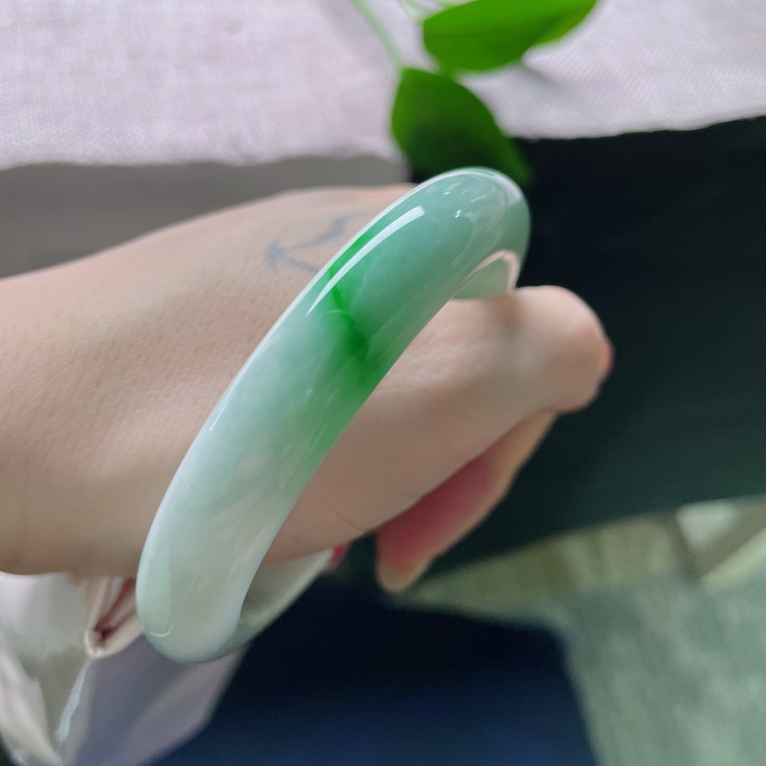 飘绿正圈，一点皮纹，几抹鲜活翠色错落晕染在镯身，绿意灵动鲜活，如同春日草木在玉底缓缓舒展。ss57981a