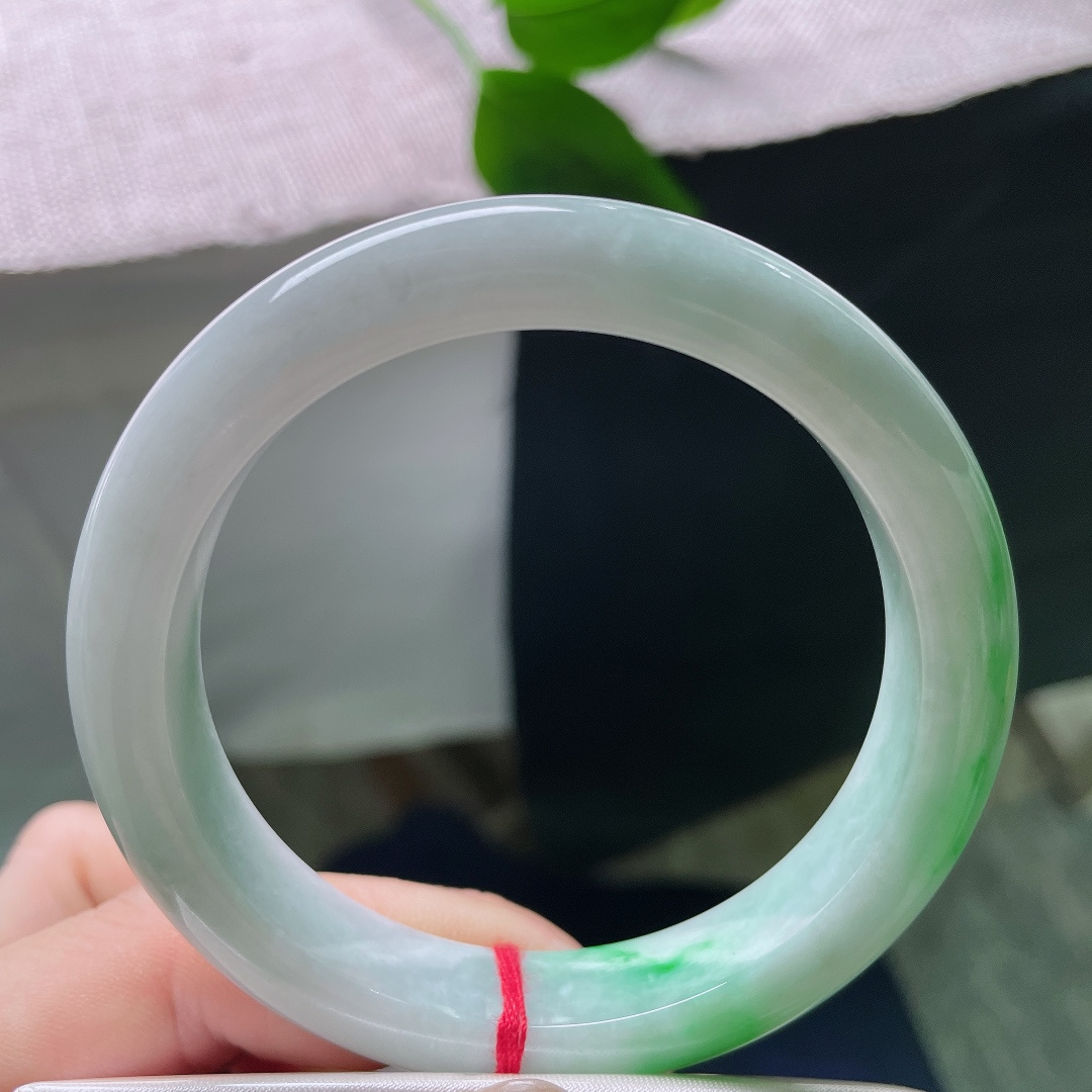 飘绿正圈，一点皮纹，几抹鲜活翠色错落晕染在镯身，绿意灵动鲜活，如同春日草木在玉底缓缓舒展。ss57981a