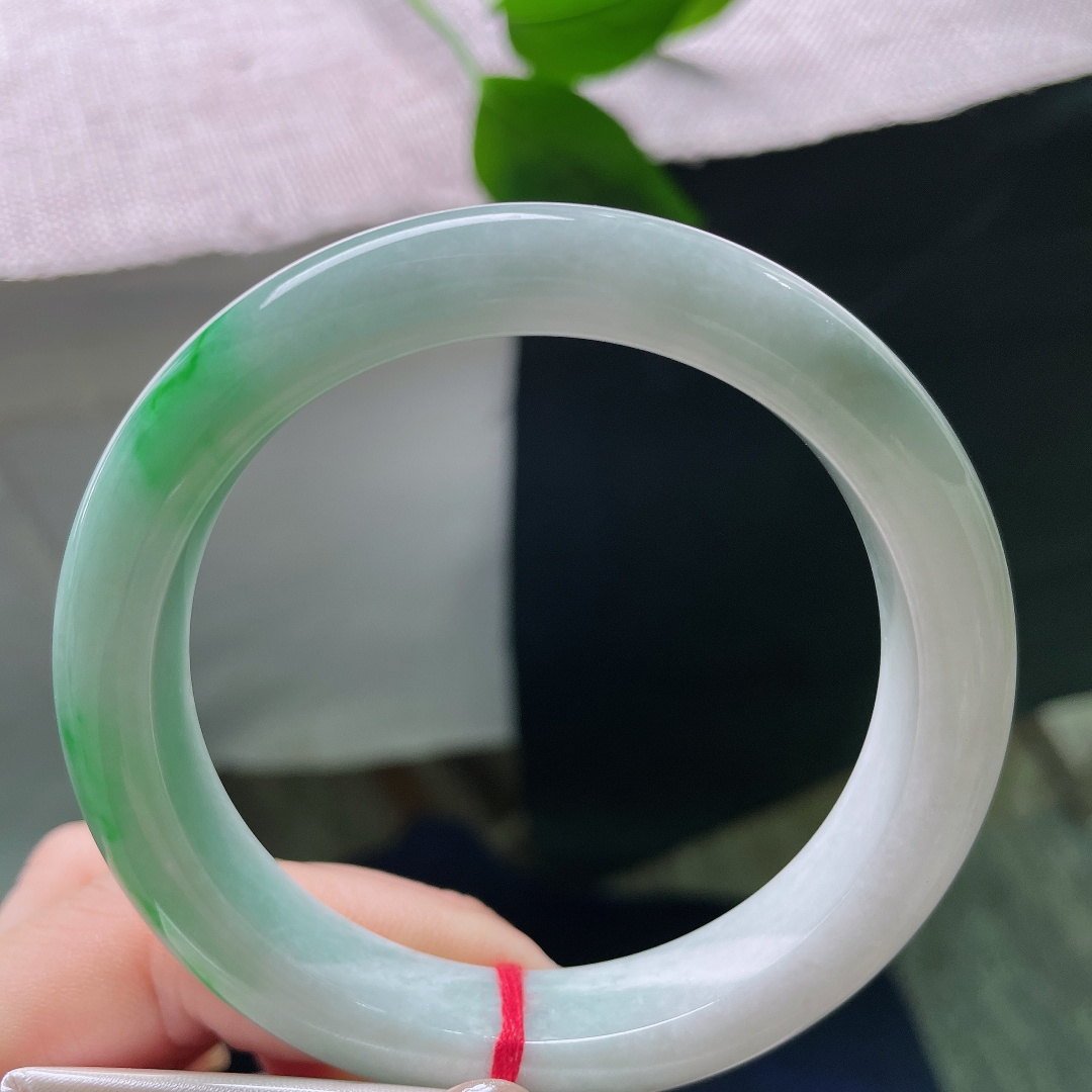 飘绿正圈，一点皮纹，几抹鲜活翠色错落晕染在镯身，绿意灵动鲜活，如同春日草木在玉底缓缓舒展。ss57981a