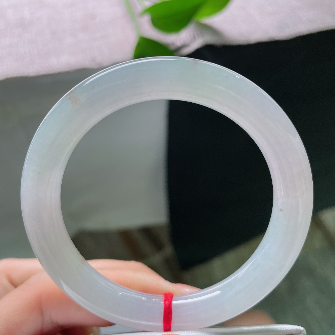 绿底圆条，无裂，洒金，镯身晕染淡淡的浅晴底色，似山间晨雾漫过玉骨，清浅朦胧，自带一份悠然空灵的诗意。