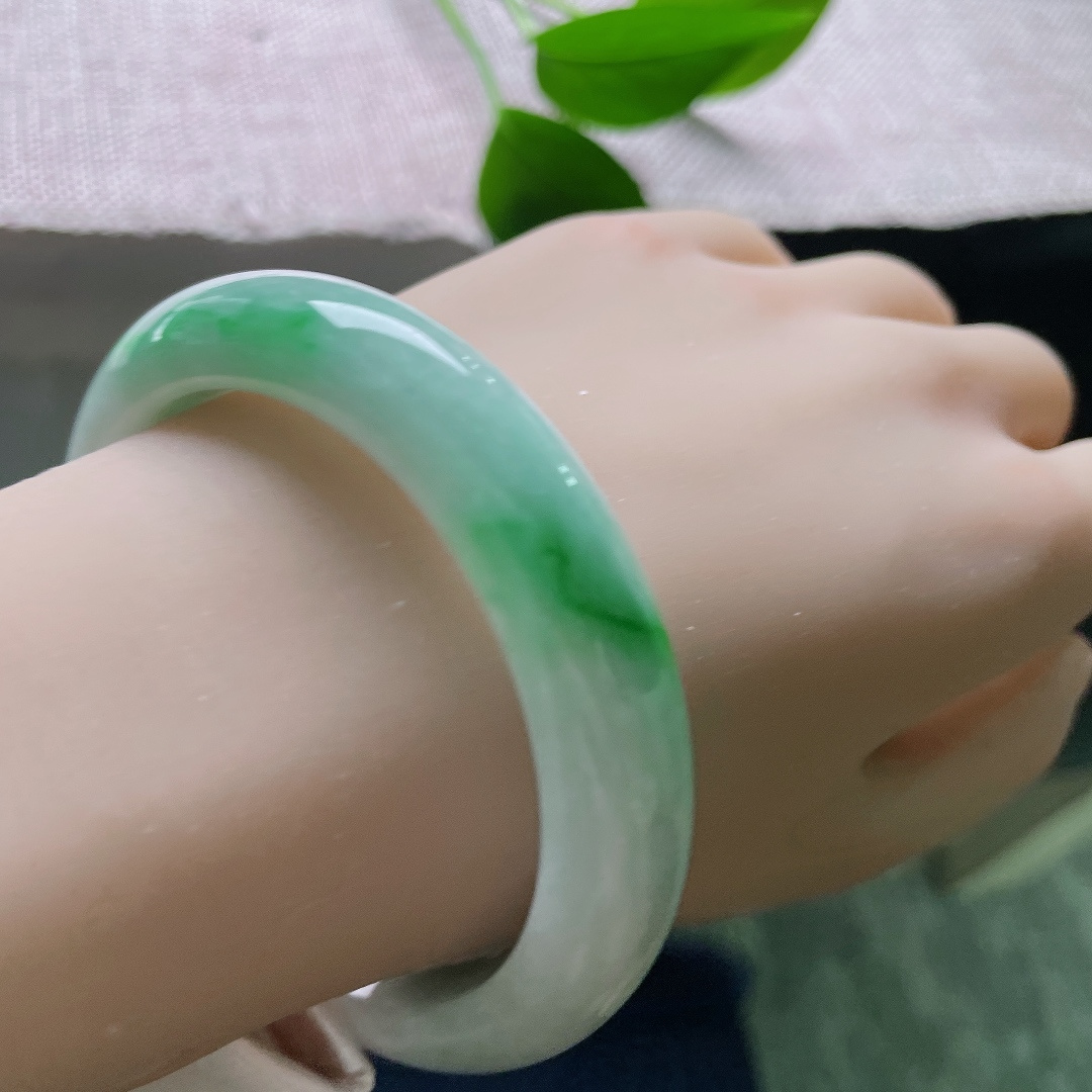 飘绿正圈，一点皮纹，几抹鲜活翠色错落晕染在镯身，绿意灵动鲜活，如同春日草木在玉底缓缓舒展。ss57981a