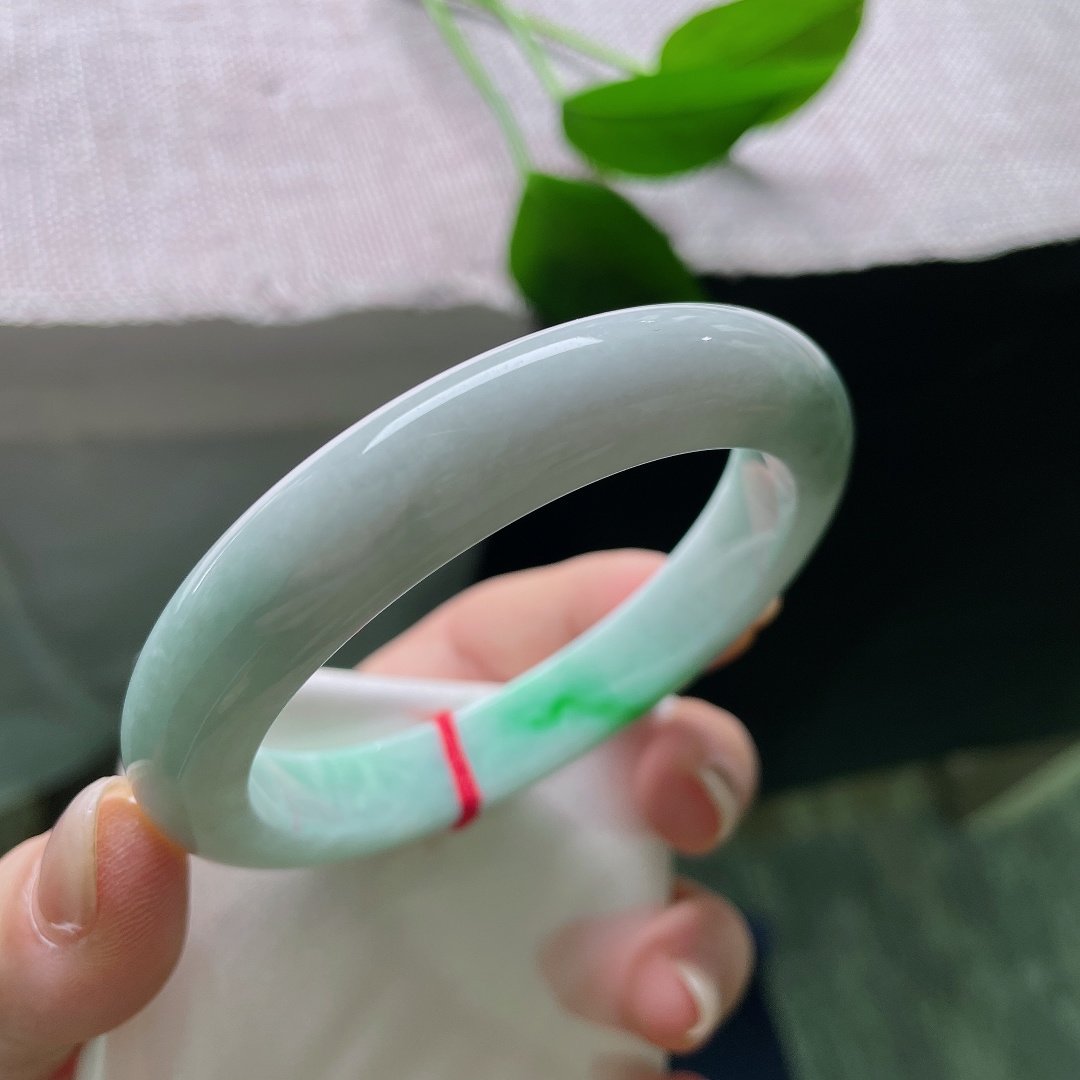 飘绿正圈，一点皮纹，几抹鲜活翠色错落晕染在镯身，绿意灵动鲜活，如同春日草木在玉底缓缓舒展。ss57981a