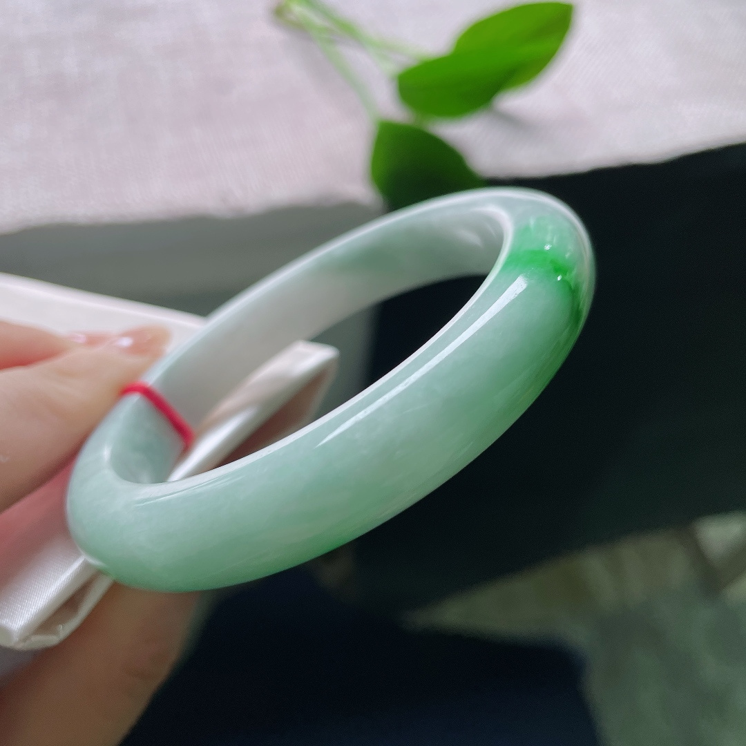 飘绿正圈，一点皮纹，几抹鲜活翠色错落晕染在镯身，绿意灵动鲜活，如同春日草木在玉底缓缓舒展。ss57981a