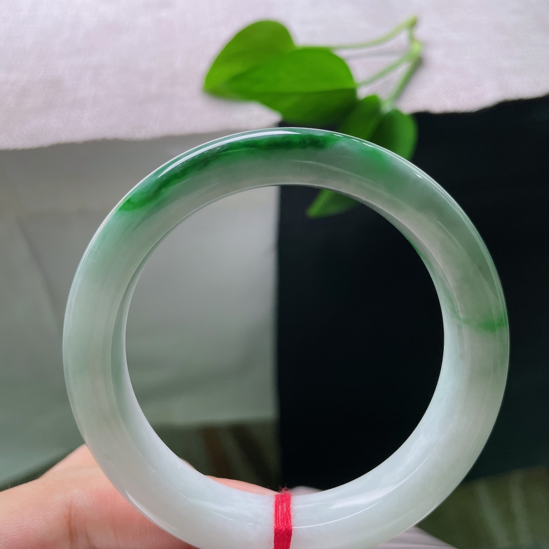 飘绿正圈，一点纹，清润冰白为底，一截浓艳辣绿环绕镯身，绿得分明亮眼，气韵张扬。ss58611a