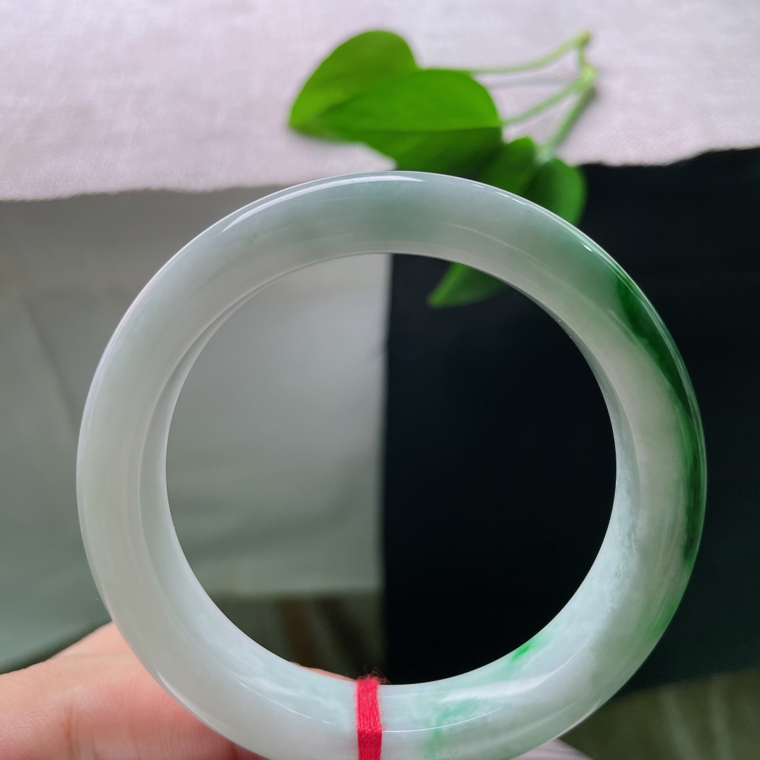 飘绿正圈，一点纹，清润冰白为底，一截浓艳辣绿环绕镯身，绿得分明亮眼，气韵张扬。ss58611a