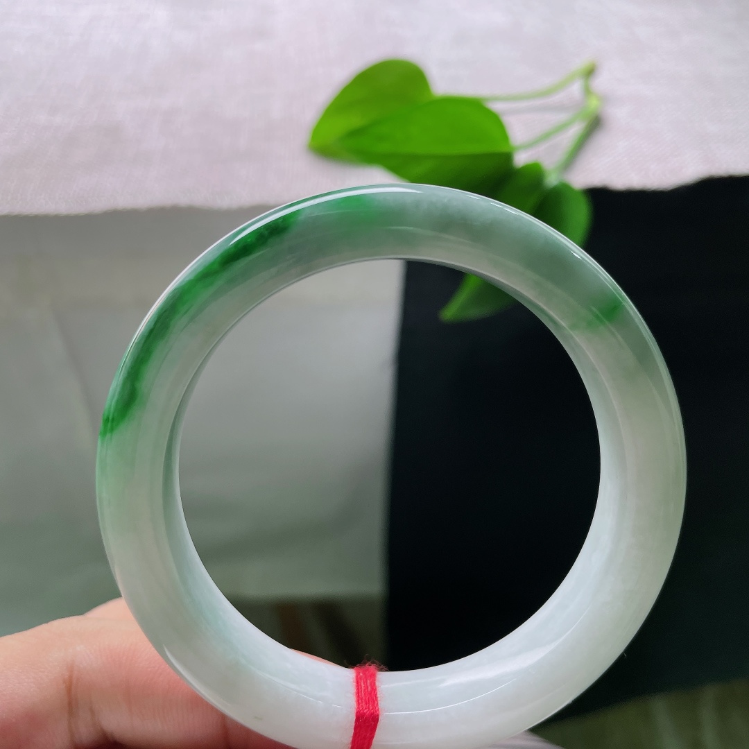 飘绿正圈，一点纹，清润冰白为底，一截浓艳辣绿环绕镯身，绿得分明亮眼，气韵张扬。ss58611a