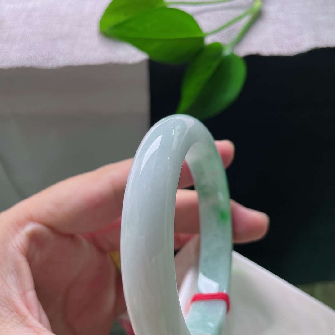 飘绿正圈，一点纹，清润冰白为底，一截浓艳辣绿环绕镯身，绿得分明亮眼，气韵张扬。ss58611a