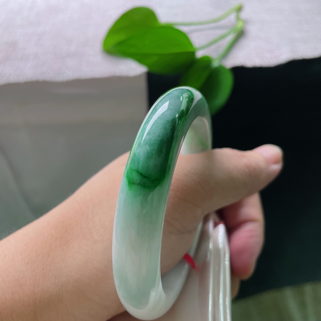 飘绿正圈，一点纹，清润冰白为底，一截浓艳辣绿环绕镯身，绿得分明亮眼，气韵张扬。ss58611a