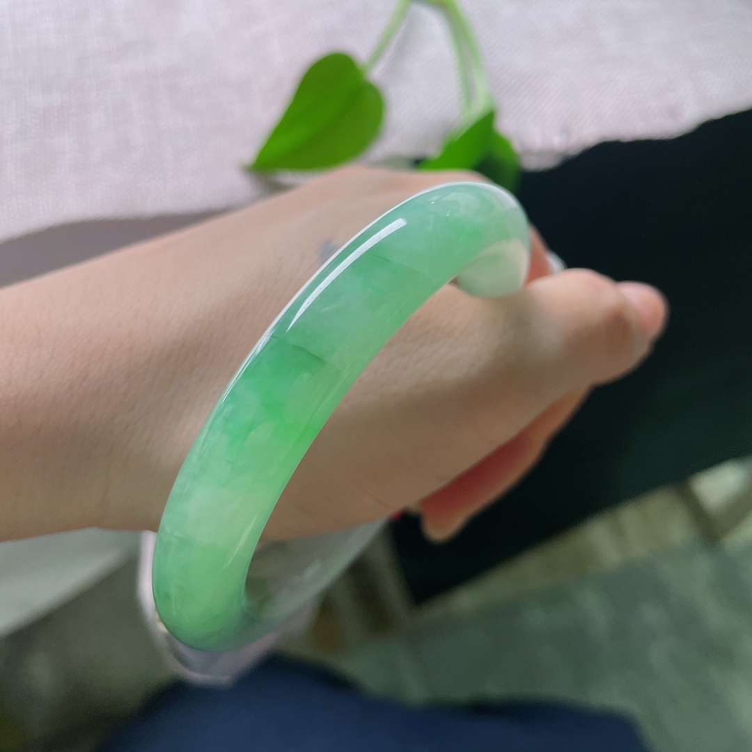 54.8/10.7，飘绿正圈，多处肉纹，玉质莹润光洁，一抹鲜亮阳绿顺势铺展在镯身，翠色鲜活灵动，上手明媚大气，一眼便是腕间亮眼风景。ss58476a