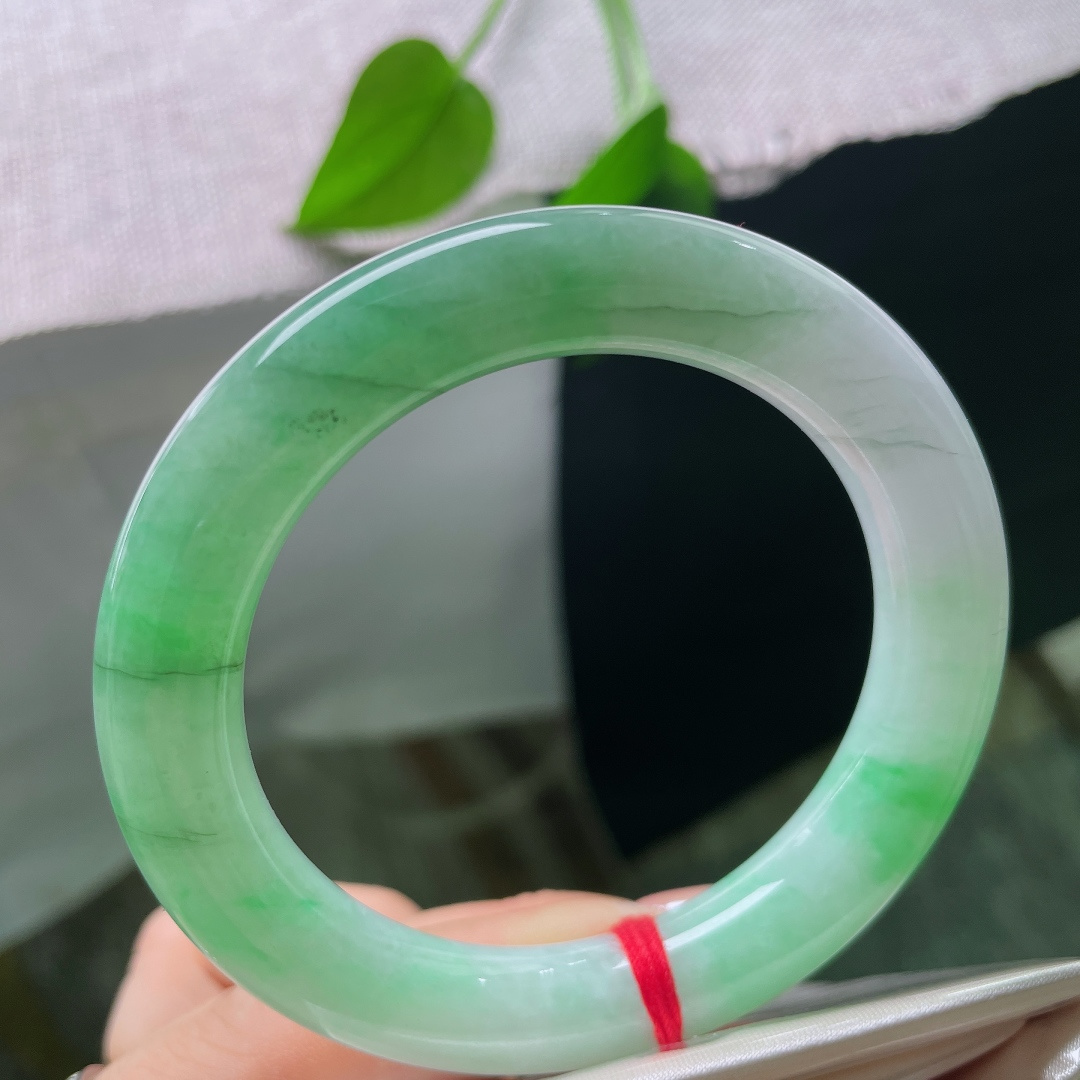 54.8/10.7，飘绿正圈，多处肉纹，玉质莹润光洁，一抹鲜亮阳绿顺势铺展在镯身，翠色鲜活灵动，上手明媚大气，一眼便是腕间亮眼风景。ss58476a