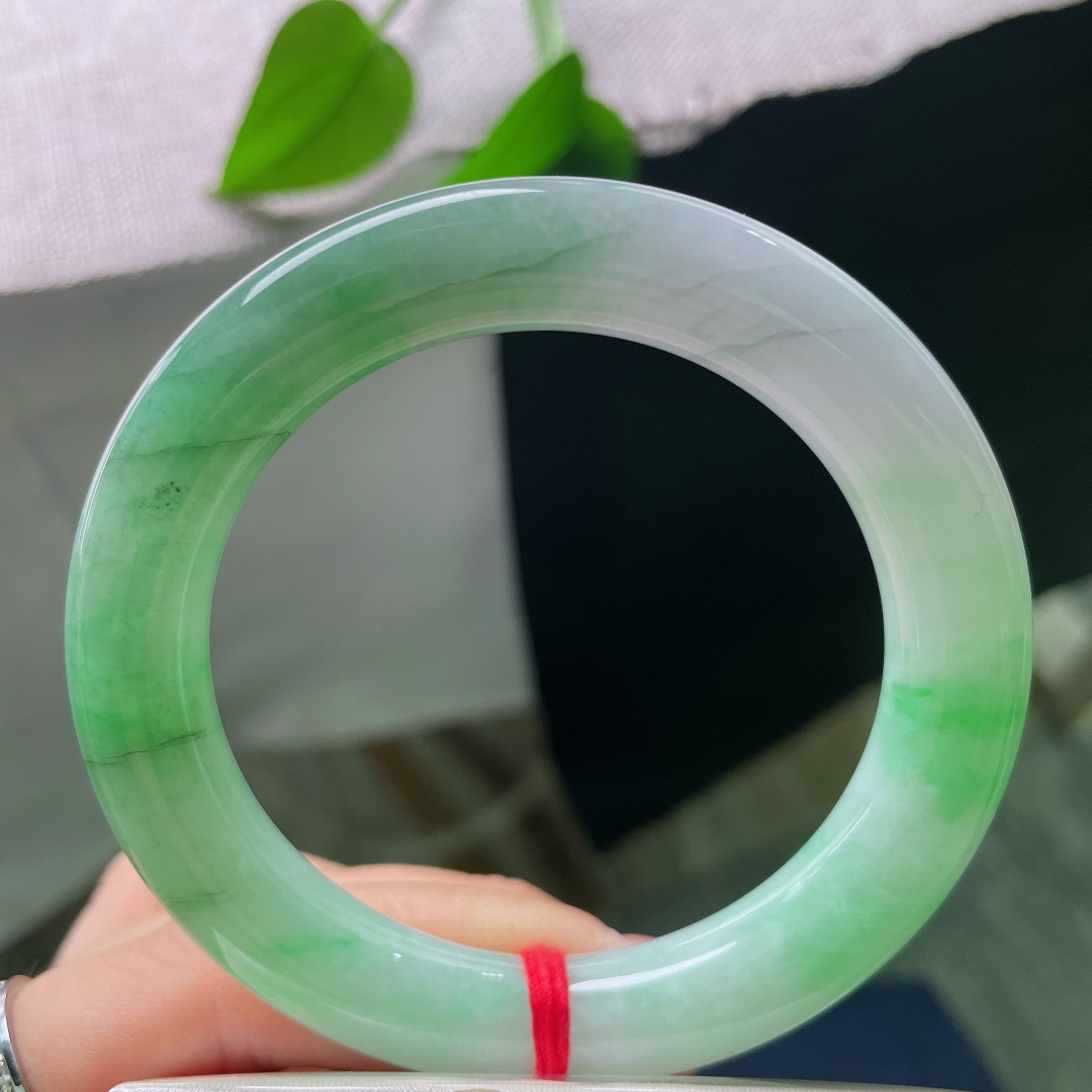 54.8/10.7，飘绿正圈，多处肉纹，玉质莹润光洁，一抹鲜亮阳绿顺势铺展在镯身，翠色鲜活灵动，上手明媚大气，一眼便是腕间亮眼风景。ss58476a