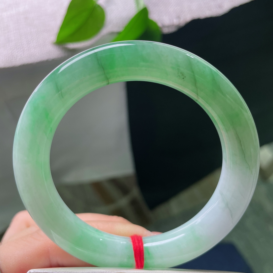 54.8/10.7，飘绿正圈，多处肉纹，玉质莹润光洁，一抹鲜亮阳绿顺势铺展在镯身，翠色鲜活灵动，上手