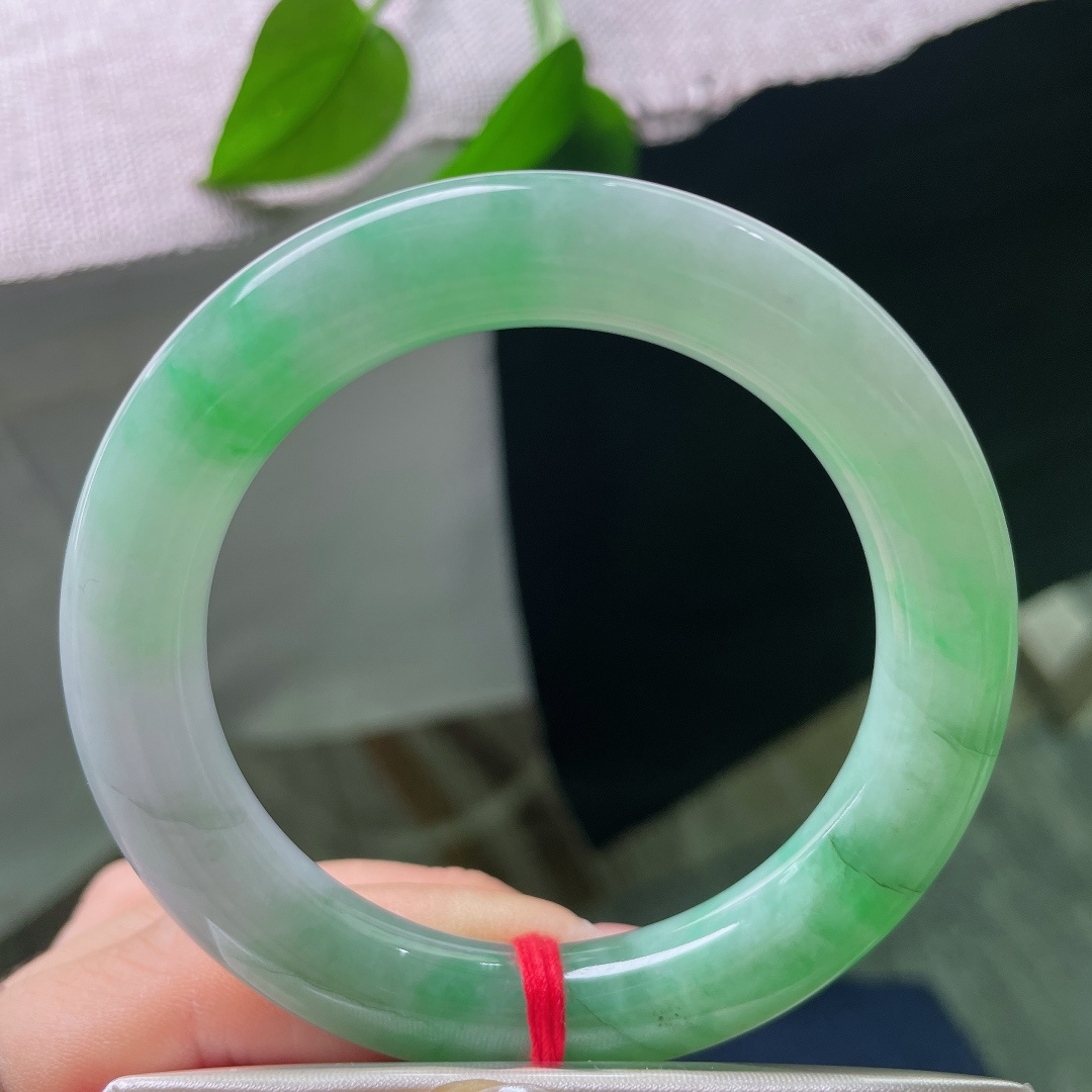 54.8/10.7，飘绿正圈，多处肉纹，玉质莹润光洁，一抹鲜亮阳绿顺势铺展在镯身，翠色鲜活灵动，上手明媚大气，一眼便是腕间亮眼风景。ss58476a