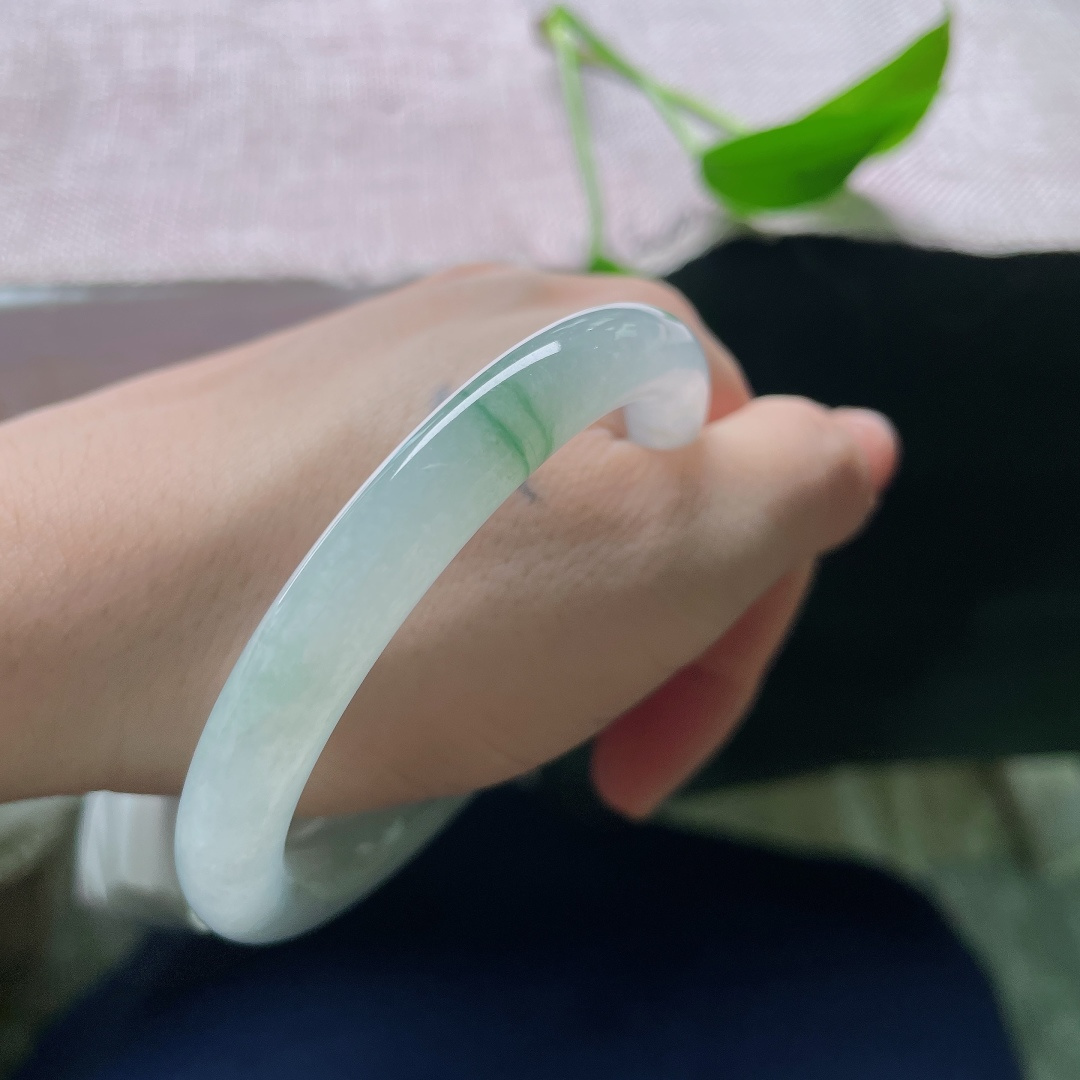 55.5/9.0，冰飘花圆条，无裂，洒金，冰润通透玉底晕染几缕翠色飘丝，光泽清莹柔和，腕间流淌出悠然清雅的山水诗意。ss58234a