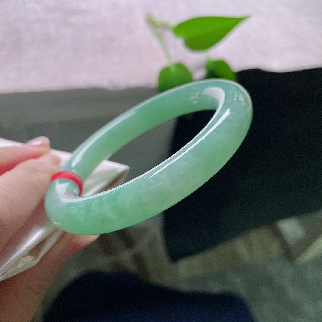 57.3/11，绿底圆条，无裂，镯身线条顺滑圆润，湖绿静谧舒缓，柔光流转，衬得肤色温润。ss59261a