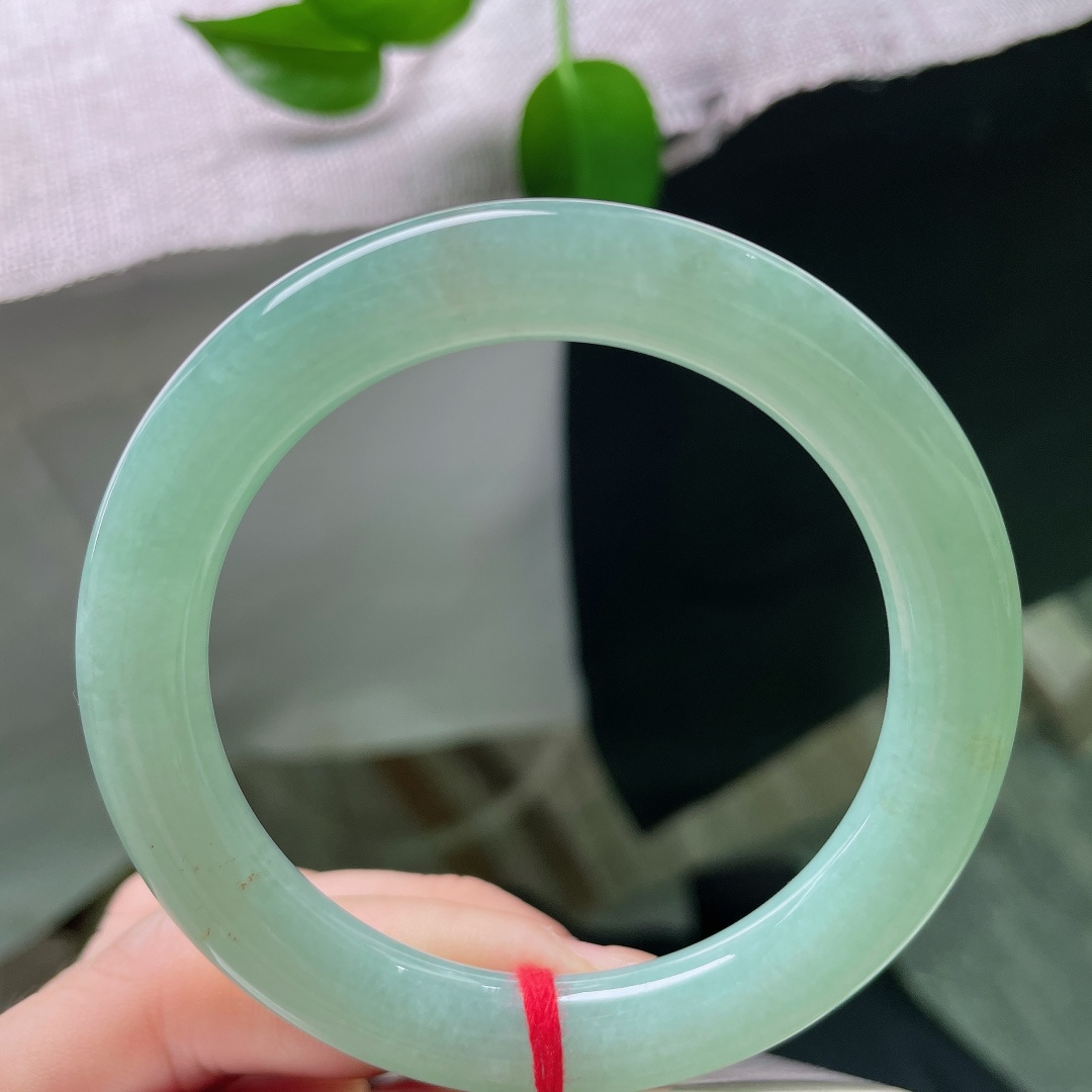 55.7/9.9，果绿圆条，棉线，镯型圆润饱满，玉质细腻，色泽恰似雨后新叶，清润鲜活，安静绽放在温润的玉镯之上。ss59644a