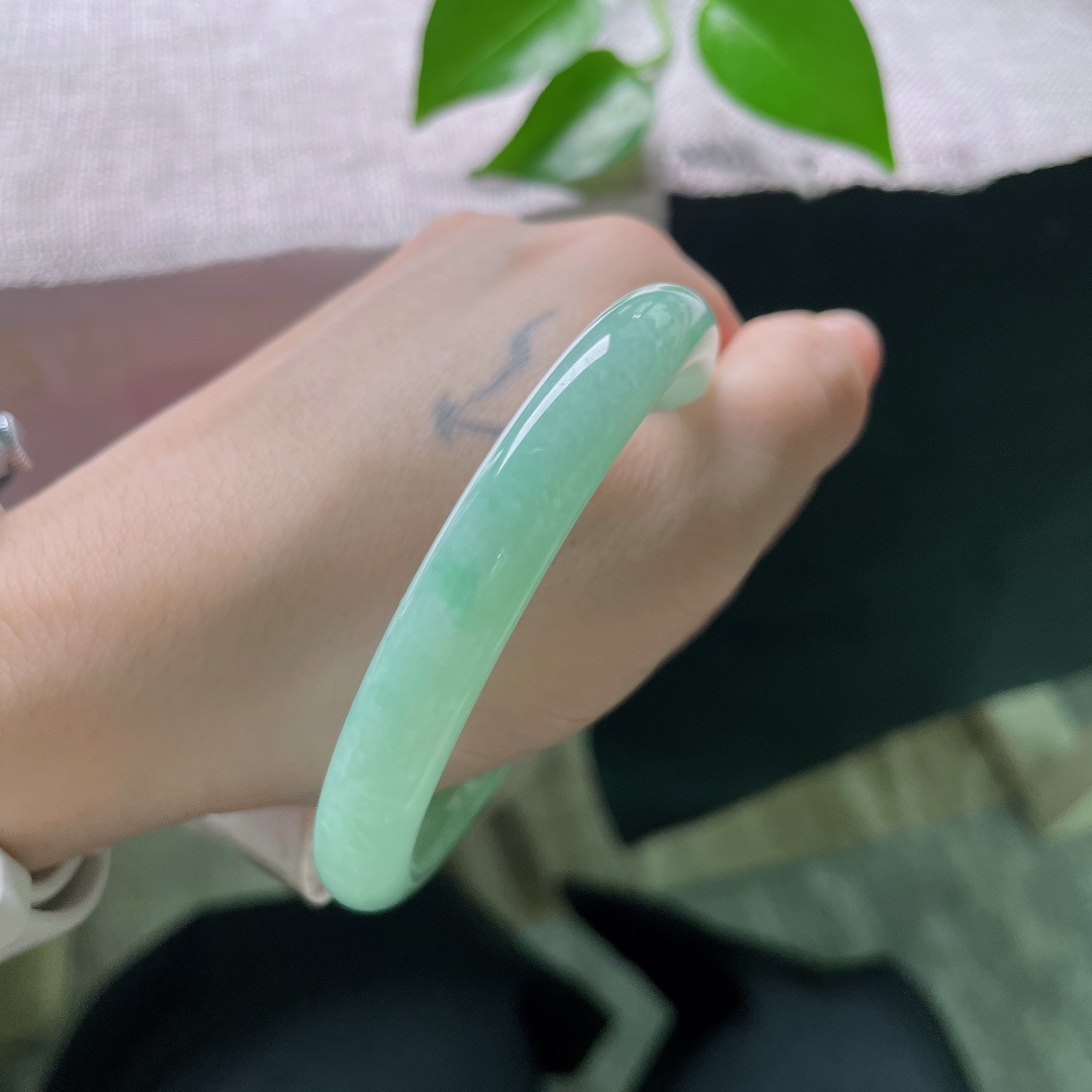 56.5/9.5，绿底圆条，无裂，圆润圆条镯身饱满敦厚，清润果绿萦绕玉间，冰感莹透，腕间漾出清新温婉古韵。ss59643a