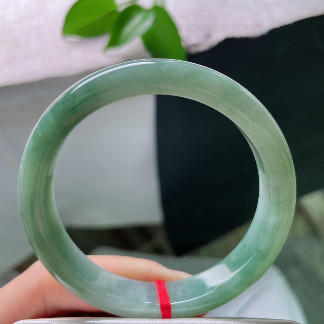 55.6/11.1/7.9，油青正圈，一点皮纹，湖水般清润底色，水头油亮，镯身晕染一抹优雅飘花，简约
