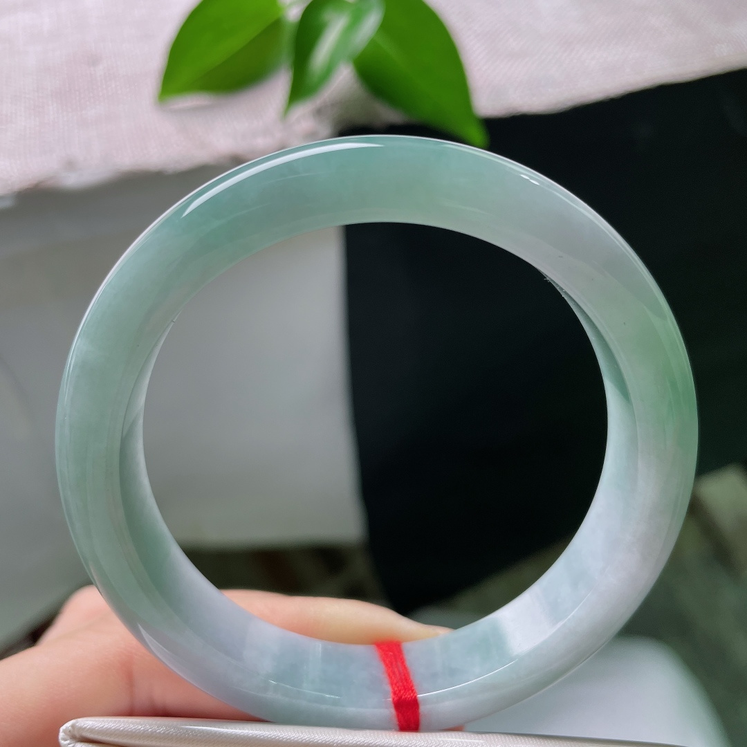 57/12/8.1，蓝底正圈，一点皮纹，冰润质地匀净莹亮，青白与翠色温柔相接，素面玉镯不加雕琢，自带