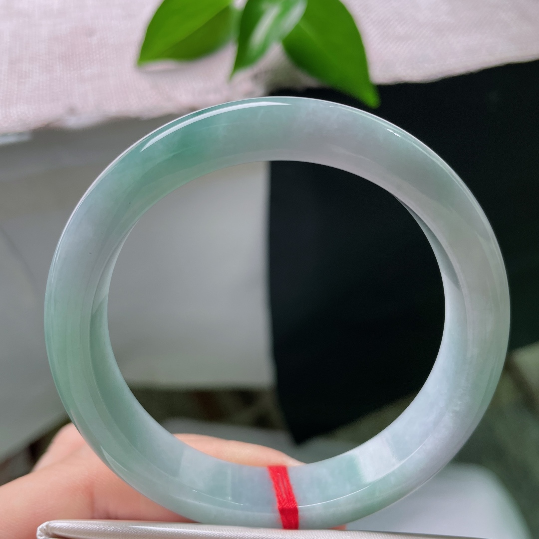 57/12/8.1，蓝底正圈，一点皮纹，冰润质地匀净莹亮，青白与翠色温柔相接，素面玉镯不加雕琢，自带沉静温润质感。ss59286a