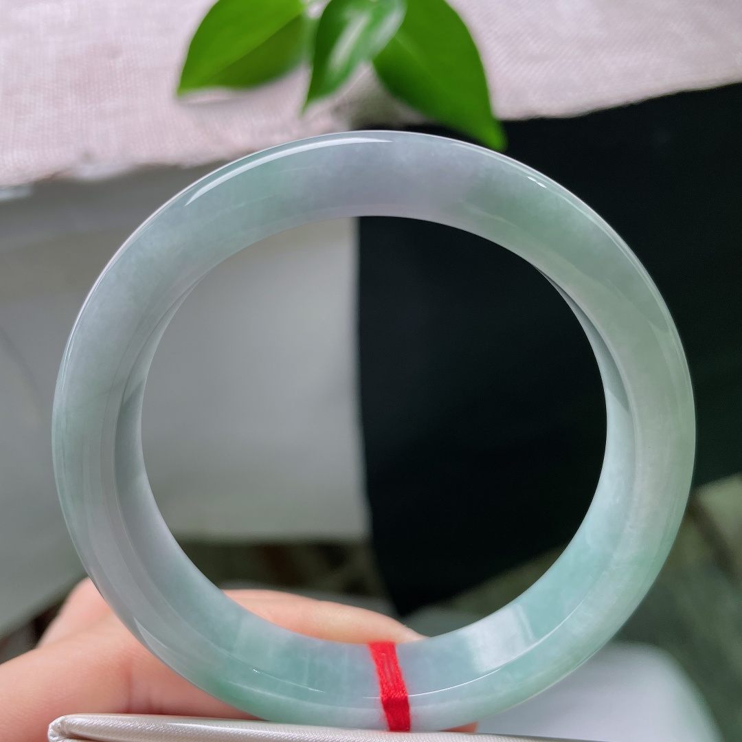57/12/8.1，蓝底正圈，一点皮纹，冰润质地匀净莹亮，青白与翠色温柔相接，素面玉镯不加雕琢，自带沉静温润质感。ss59286a