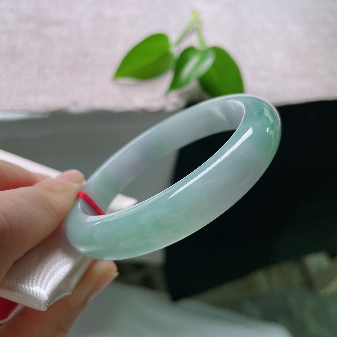 57/12/8.1，蓝底正圈，一点皮纹，冰润质地匀净莹亮，青白与翠色温柔相接，素面玉镯不加雕琢，自带沉静温润质感。ss59286a