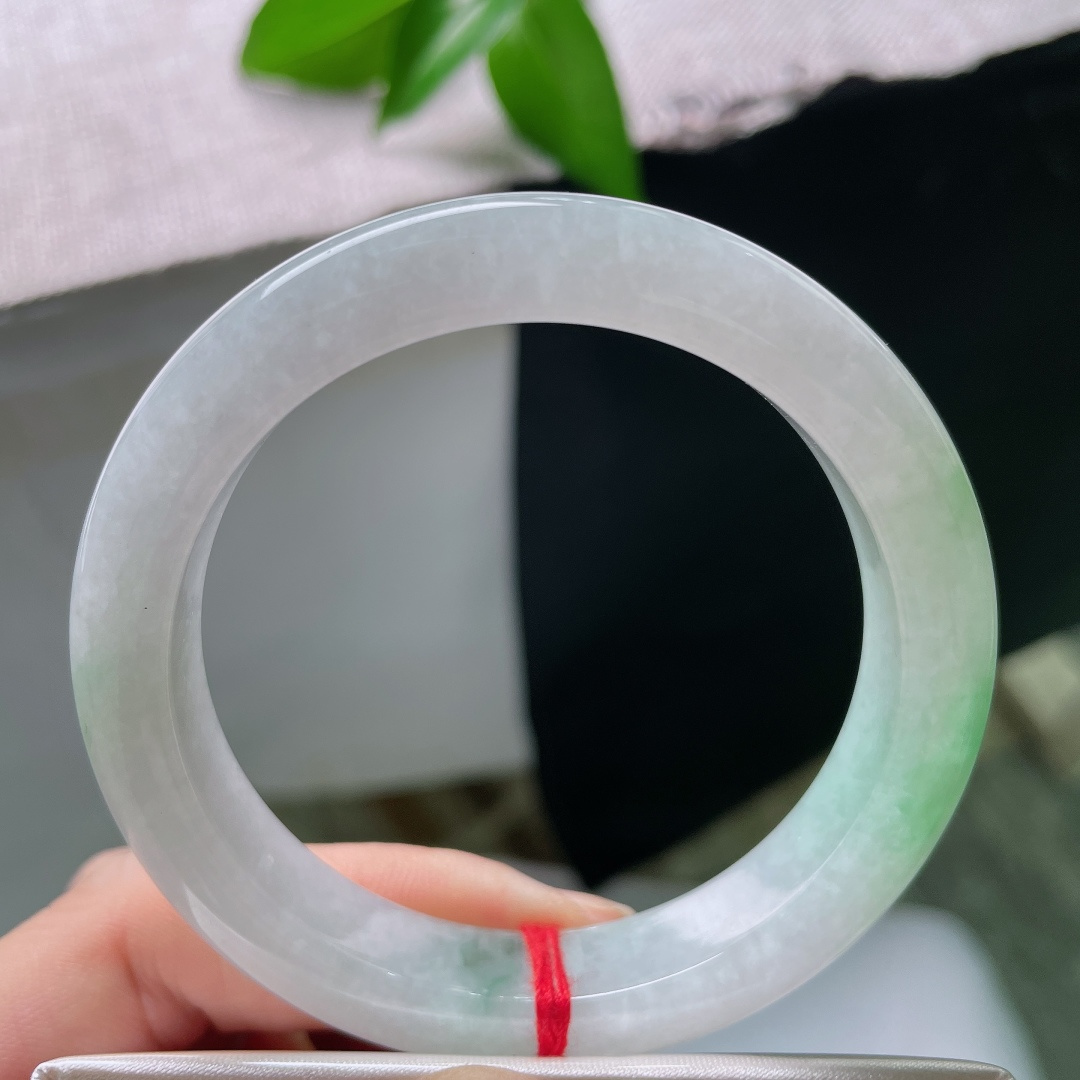 55/11/9，飘绿正圈，一点皮纹，玉以清润浅白为底，一抹鲜翠悠然落于镯身，似将春日林间的一缕青绿凝