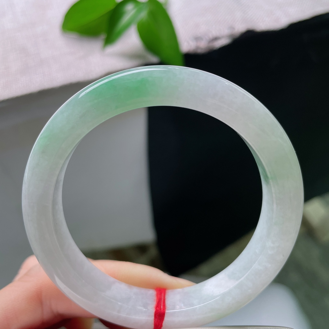 55/11/9，飘绿正圈，一点皮纹，玉以清润浅白为底，一抹鲜翠悠然落于镯身，似将春日林间的一缕青绿凝