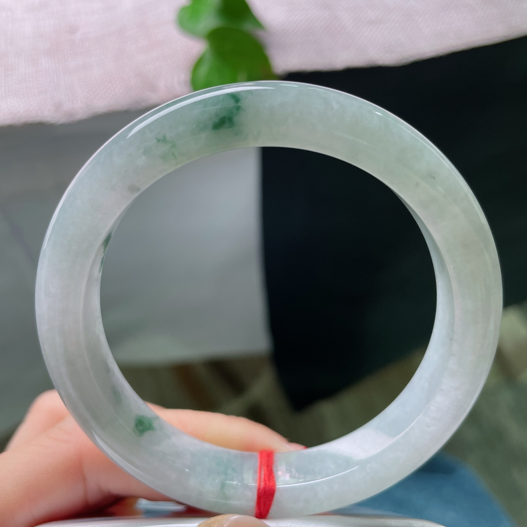 57.7/11.2/9.2，飘花正圈，无裂，冰底凝翠，柔光漫过素玉圆镯，零星绿丝随性晕开，将一池清潭